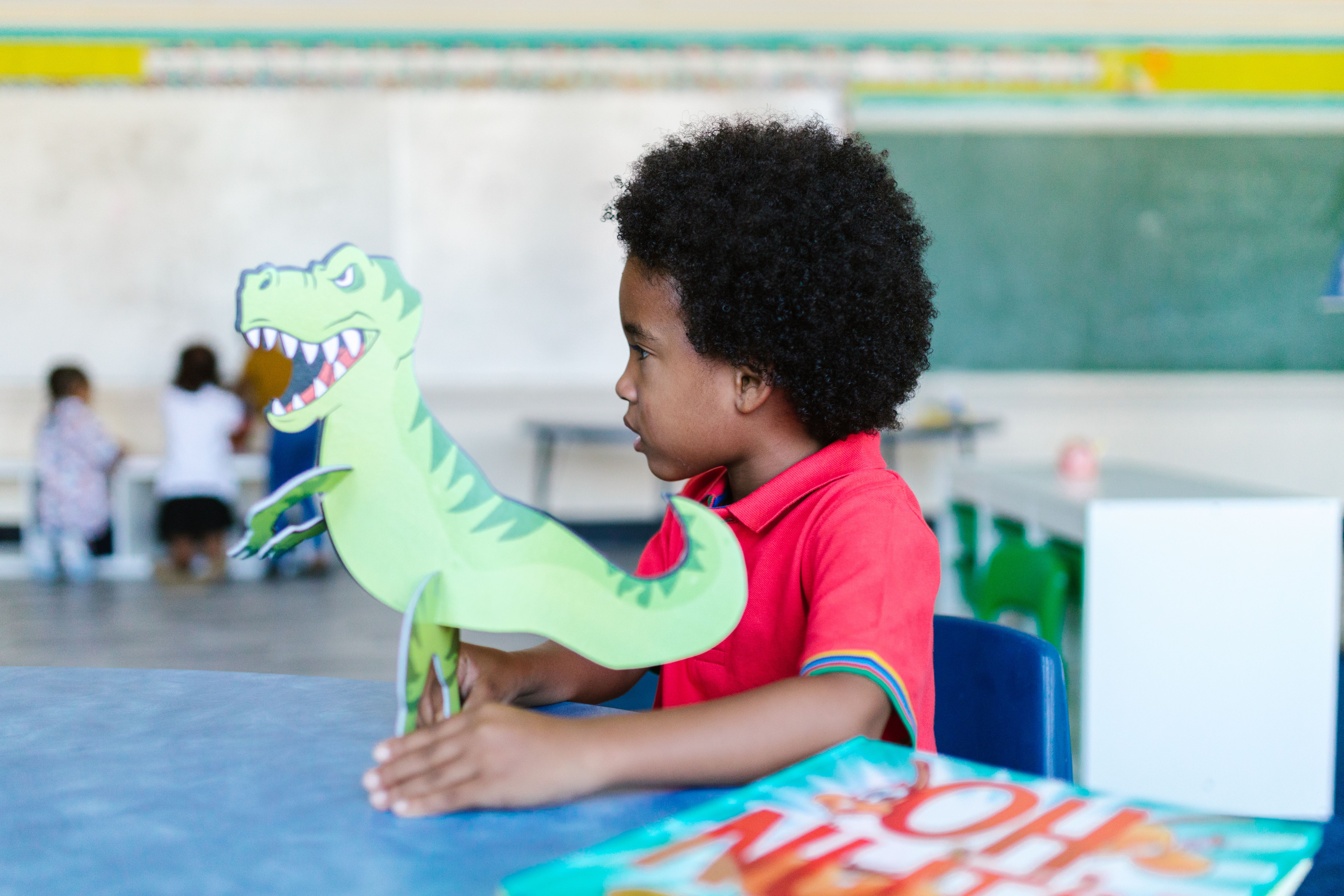 Child holding a dinosaur activity in a classroom